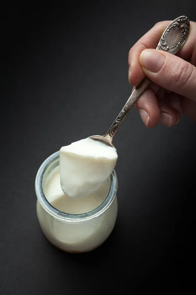 Organic homemade yogurt in a glass cup. A hand takes a spoon on — Stock Photo, Image