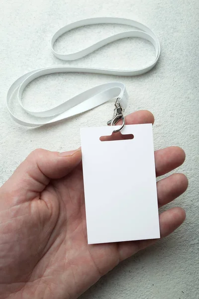 Targhetta con nome vuoto e cinturino bianco in mano, mockup . — Foto Stock