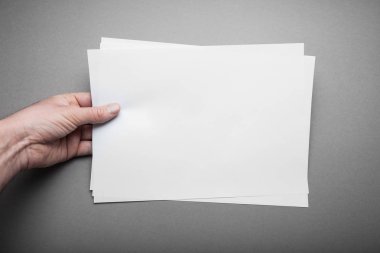 Bir erkek Europea gri bir arka plan boş yatay A4 kağıda