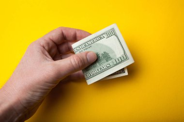 Bent yüz dolarlık banknot elinde açık bir sarı arka plan, satış veya