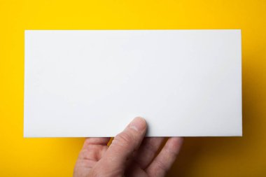 Boş beyaz Dl el ilanı Sarı zemin üzerine elinde. Mockup, yatay