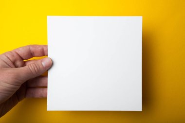 Sarı bir arka plan üzerinde elinde boş kare düzen.