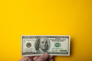 Amerikan Doları sarı bir arka plan üzerinde elinde. Kopya alanı.