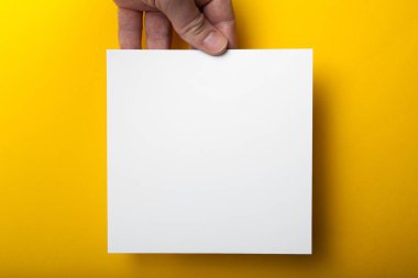 Sarı bir arka plan üzerinde elinde bir kare beyaz mocap.