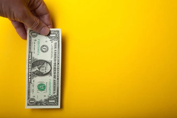 Een dollarbiljet in hand op een gele achtergrond, een grote verkoop. Empt — Stockfoto