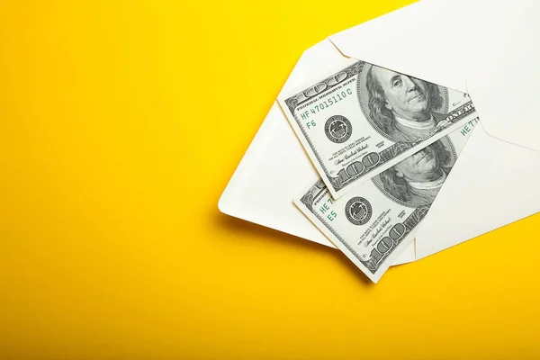 Twee honderd-dollarbiljetten in een envelop geïsoleerd op een gele bac — Stockfoto