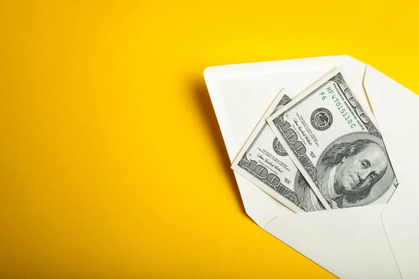 Dollars in een envelop op een gele achtergrond. — Stockfoto