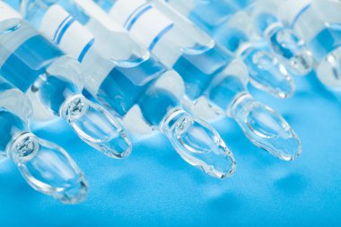 Mavi bir arka plan üzerinde vitaminler ile şeffaf ampul.