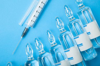 Ampul ve şırınga mavi zemin üzerine.