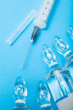 Mavi arka planda tıbbi ampuller ve şırınga.