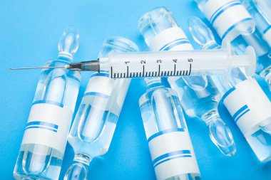 Aşı şişeleri mavi zemin üzerine şırınga.