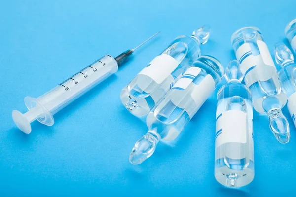 Tıbbi ampül ve üzerinde mavi arka plan izole şırınga.