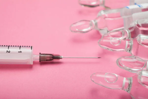 Spruta med en nål och ampuller på en rosa bakgrund. — Stockfoto