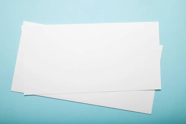 Duas folhas de papel em branco num fundo azul. Espaço de cópia . — Fotografia de Stock