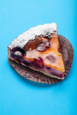 Bir dilim kirazlı turta mavi bir arka plan üzerinde izole.