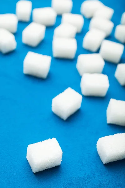 Fundo vertical de cubos espalhados de açúcar em um backgr azul — Fotografia de Stock