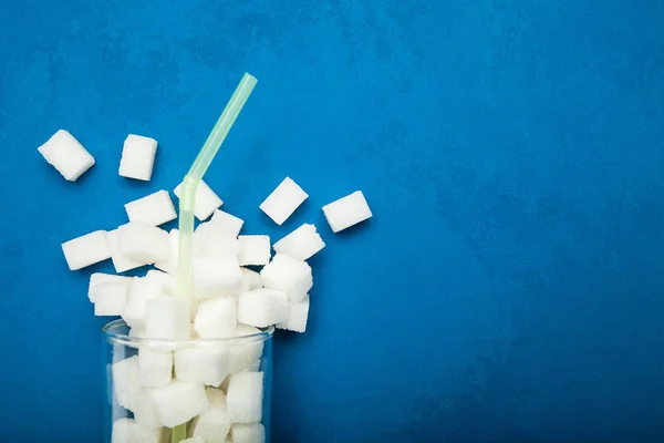 Verschütteter Zucker aus einem Glas auf blauem Hintergrund. Riesenzucker — Stockfoto