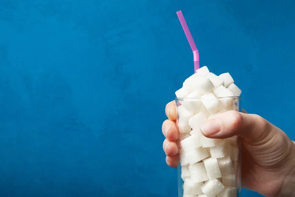 Die Hand hält ein Glas mit Zucker auf blauem Hintergrund. die conc — Stockfoto