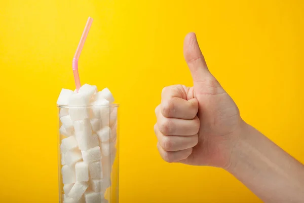 Azúcar en un frasco de vidrio aislado sobre un fondo amarillo, pulgar hacia arriba . — Foto de Stock