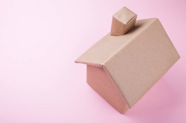 Bir karton ev pembe bir arka plan üzerinde. Yukarıdan görüntülemek