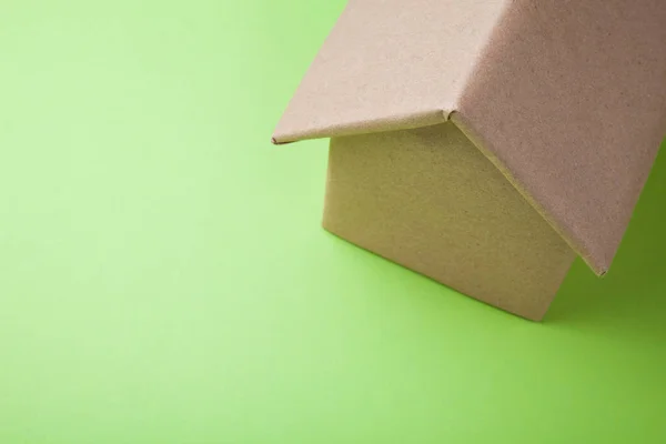 Casa de papelão em um fundo verde . — Fotografia de Stock