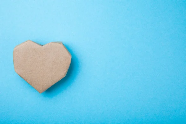 Romantic heart made of recycled cardboard on a blue background,