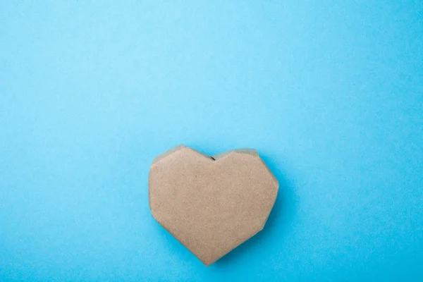 Homemade heart made from recycled paper on a blue background, em