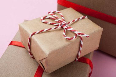 Küçük el yapımı Hediyelik kutu pembe bir arka plan üzerinde kırmızı kurdele ile