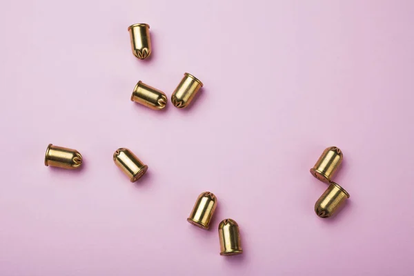 Cartouches et balles vides dorées renversées sur fond rose — Photo