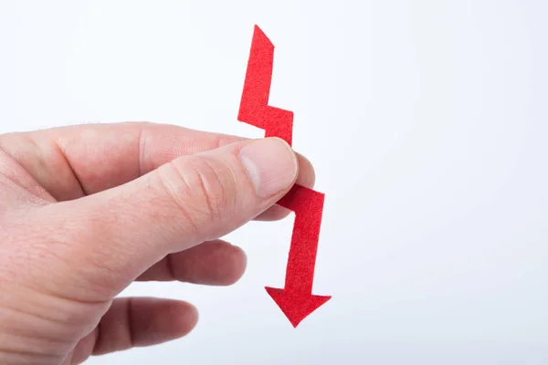 Red arrow in hand, as a symbol of financial fall. — Stock Photo, Image