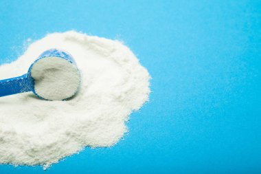 Plastik kaşık süt tozu üzerinde mavi bir arka plan boş boşluk ile
