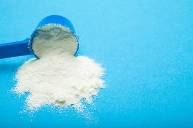 Dökülen süt tozu kaşık ölçme bir mavi. Kopya alanı.