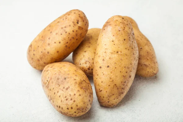 Fresh young potatoes on a white table. — Stock Photo, Image