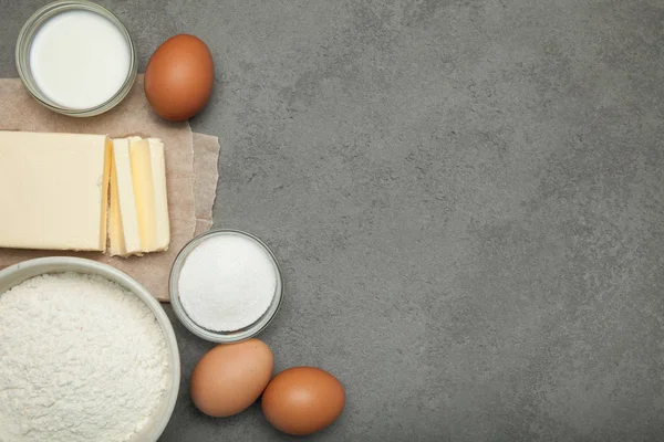 Çiğ yumurta, tereyağı, un ve şekerle gri bir arka plan üzerinde süt — Stok fotoğraf