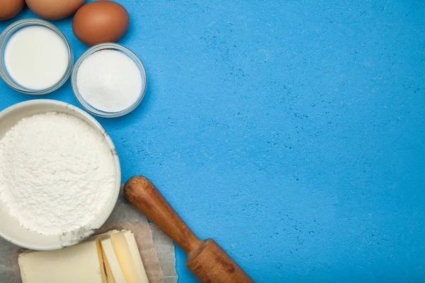 Ingrediënten voor het koken: suiker, eieren, meel en olie op een blauwe ba — Stockfoto