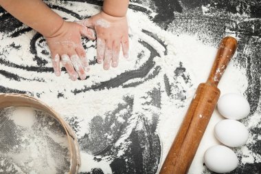 Çocuk elinde un, elek, oklava.