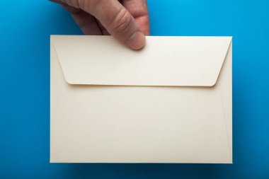 Üzerinde mavi arka plan izole elinde boş zarf.