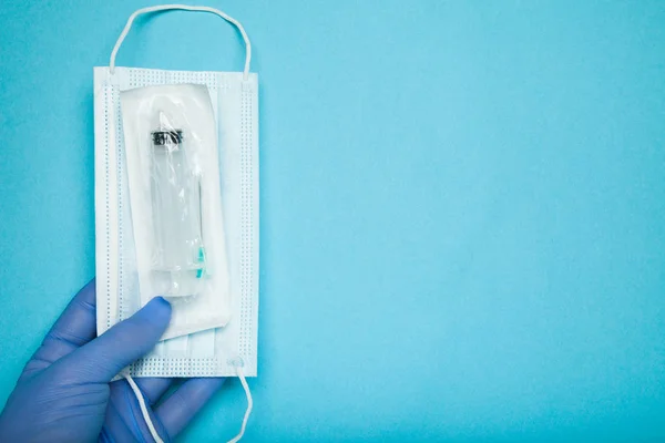 En blå-handskar hand håller en steril spruta och mask. Immunizatio — Stockfoto