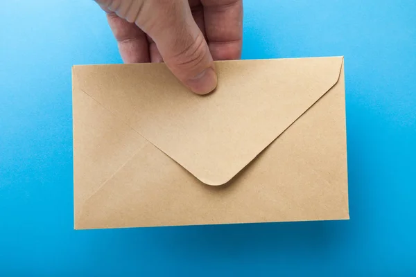 Amplop surat dari kertas daur ulang di tangan pada latar belakang biru — Stok Foto