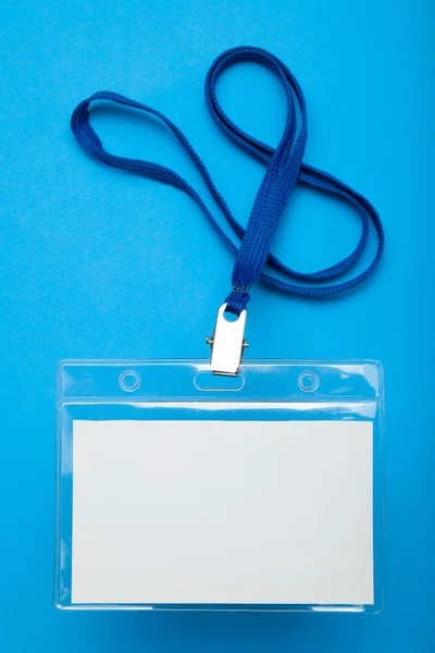 Name tag badge with lanyard on blue background.