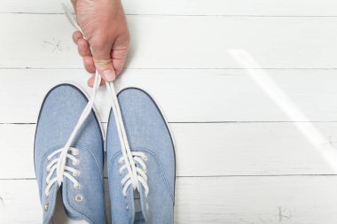 El beyaz bir ahşap ba üzerinde bağcıklar tarafından mavi kot spor ayakkabı tutar