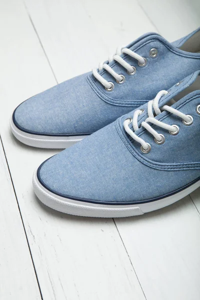 Beyaz ahşap arka plan üzerinde yumuşak rahat mavi spor ayakkabı, ver