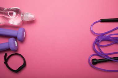 Pembe arka planda parlak spor aksesuarları. Metin için boş alan.