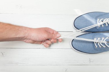 Hafif ahşap arka plan üzerinde şık ayakkabılar, el bağcıkları çeker.