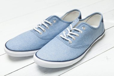Beyaz arka planda mavi denim rahat spor ayakkabılar.
