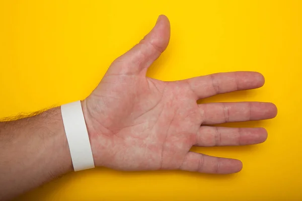 Mão com um papel branco pulseira em branco . — Fotografia de Stock