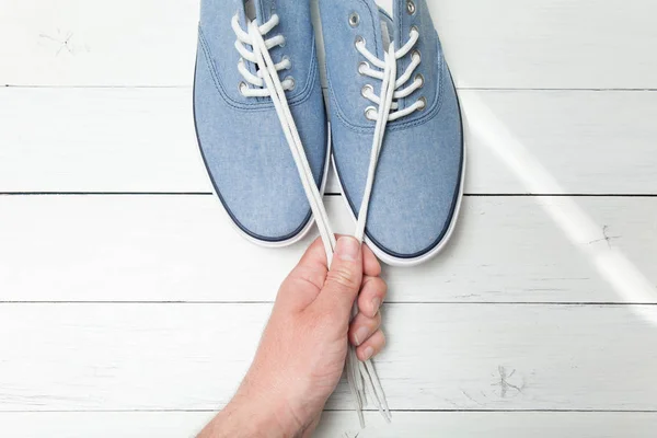 밝은 나무 배경에 유행 신발, 손에 흰색 끈. — 스톡 사진