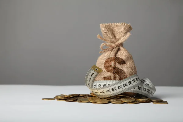 Bag with money and measuring tape on gold coins. Lack of money,