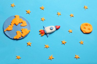 Açık alanda yaratıcı el yapımı plastik roket, astronot rüyaları. Yıldızlar, dünya ve ay gezegeni. Çizgi film sanatı.