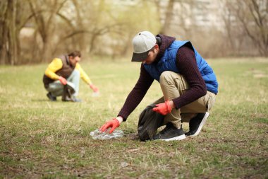 Bağış gönüllüleri ormandaki çöpleri topluyor, doğayla ilgileniyor. Parkta bahar temizliği, çöpler ve çöpler..